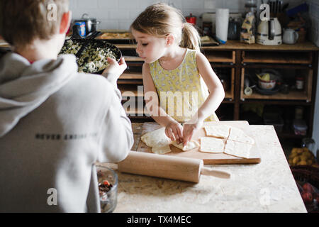 Ragazzina e suo fratello maggiore preparazione di pasta ripiena in cucina Foto Stock