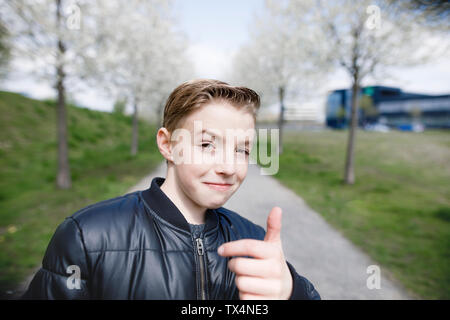 Ragazzo adolescente in un parco dando pollice in alto Foto Stock