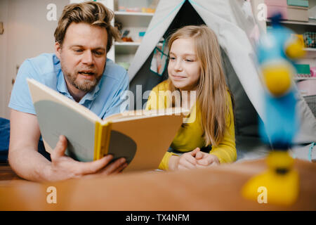 Padre e figlia a casa Leggere libro nella stanza dei bambini Foto Stock