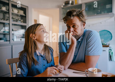 Figlia di parlare al padre nella cucina di casa Foto Stock