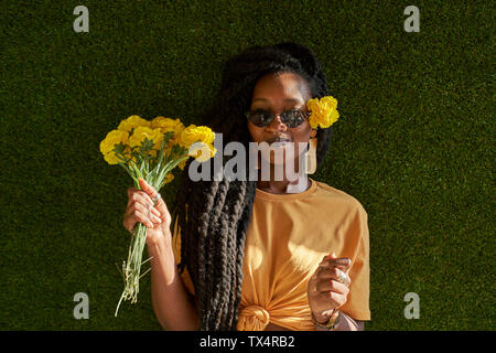 Giovane donna con dreadlocks holding fiori Foto Stock