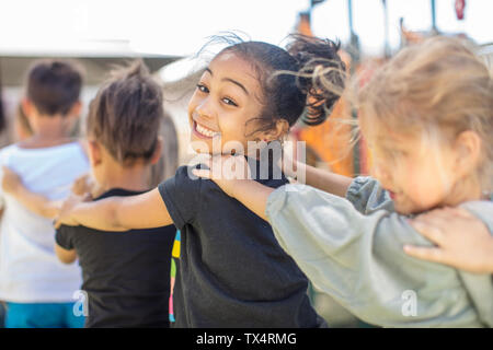 Dei bambini felici facendo una linea conga in kindergarten Foto Stock