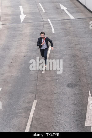 Imprenditore in esecuzione su strada con freccia segni Foto Stock