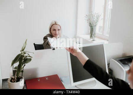 Due giovani donne che lavorano alla scrivania in ufficio consegna carta Foto Stock