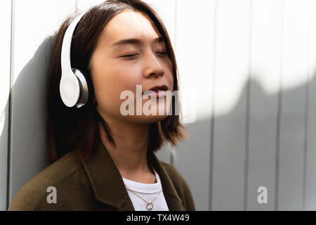 Rilassata giovane donna con gli occhi chiusi per ascoltare musica con le cuffie Foto Stock