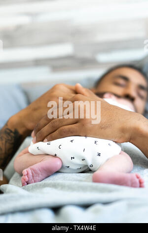 Uomo dorme nel letto tenendo il suo neonato Foto Stock