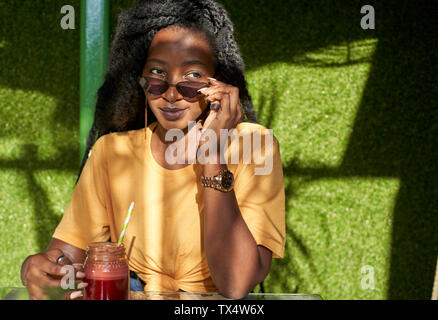 Giovane donna con dreadlocks avente un smoothie in un cafe Foto Stock