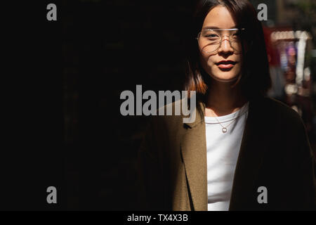 Ritratto di giovane donna che indossa gli occhiali in presenza di luce solare Foto Stock