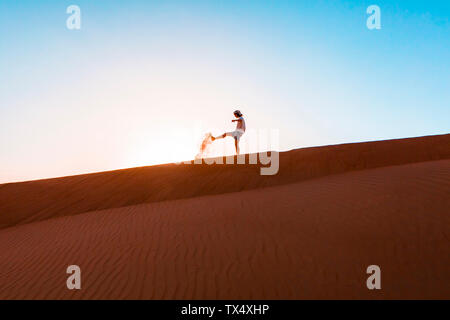 Il sultanato di Oman, Wahiba Sands, metà uomo adulto è il gioco con la sabbia nel deserto Foto Stock