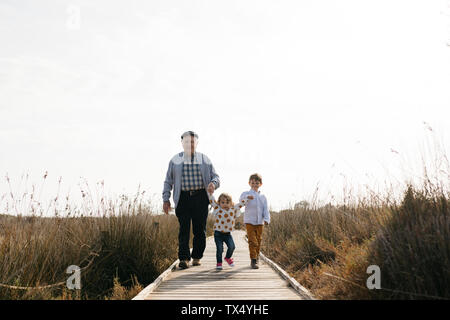 Nonno e nipoti passeggiando mano nella mano sul lungomare Foto Stock