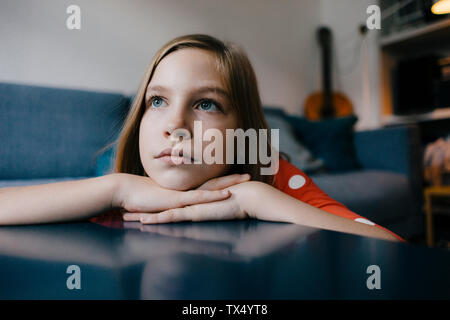 Ragazza seria in appoggio la sua testa sul tavolino da caffè a casa Foto Stock