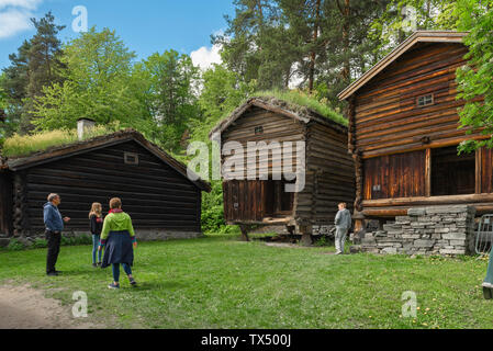 I turisti guardano in legno tradizionali magazzini risalenti al XVIII e XIX secolo situato nel Norsk Folkemuseum in Bygdøy, Oslo, Norvegia Foto Stock