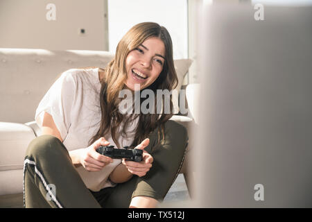 Felice giovane donna la riproduzione di video gioco a casa Foto Stock