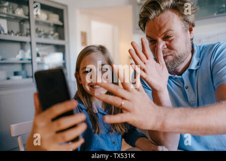 Giocoso padre e figlia prendendo un selfie a casa Foto Stock