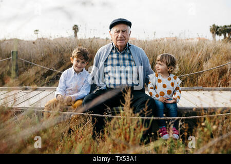 Ritratto di nonno seduto con i suoi nipoti affiancate sul Boardwalk Foto Stock