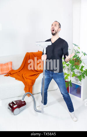 Un uomo cantano con un aspirapolvere. Foto Stock