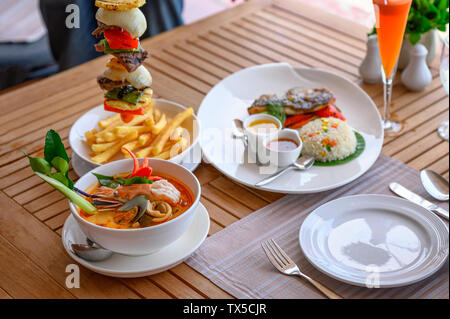 Tom Yum kung zuppa piccante con carne di manzo, pesce fritto riso su un tavolo di legno Foto Stock