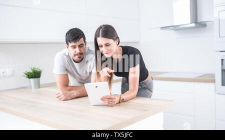 Coppia giovane nella cucina di casa utilizzando un tablet. Foto Stock