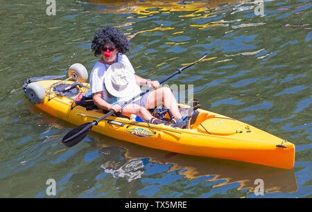 Uomo che indossa parrucca e naso rosso in kayak Hobie divertirsi su Dorset Dinghy giorno sul Fiume Stour, Iford, Dorset Regno Unito nel mese di giugno Foto Stock