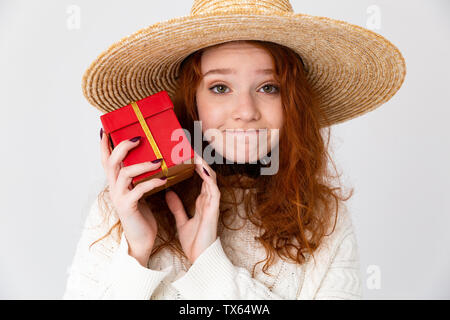 Close up ritratto di un allegro giovane ragazza adolescente che indossa estate hat in piedi isolato su sfondo bianco, che mostra la presente casella Foto Stock