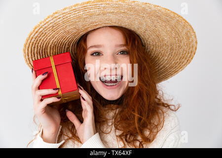 Close up ritratto di un allegro giovane ragazza adolescente che indossa estate hat in piedi isolato su sfondo bianco, che mostra la presente casella Foto Stock