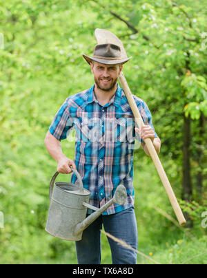 La piantumazione di alberi di tradizione. La coltivazione di piante. Coppia guy cappello da cowboy con annaffiatoio e pala. Arbor Day. La piantagione di alberi. Impegno e responsabilità. Concetto di agricoltura. La semina in giardino. Foto Stock