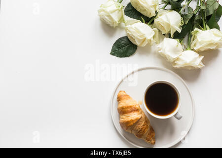 Tazza di caffè e un croissant appena sfornato su sfondo bianco. Vista dall'alto. Copia dello spazio. Foto Stock