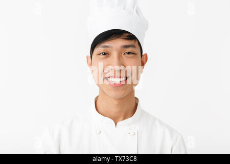 Emozionato chef asiatico che indossano uniformi isolato permanente su sfondo bianco Foto Stock