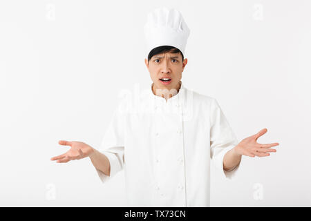 Confuso chef asiatico che indossano uniformi isolato permanente su sfondo bianco Foto Stock