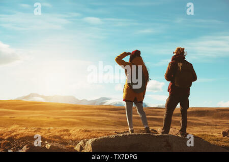 Due backpackers o viaggiatori sorge sulla grande roccia e guarda alle montagne Foto Stock