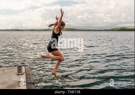 Bantry, West Cork, Irlanda. Il 24 giugno 2019. Lily Upton da Durrus salti in acqua nella baia di Bantry per rinfrescarsi in un ambiente molto caldo e umido giorno nel West Cork con temperature che raggiungono i 23°C. Incontrato Eireann ha rilasciato una tempesta gialla di avviso meteo, che è in posizione fino a 10pm stasera. Credito: Andy Gibson/Alamy Live News. Foto Stock