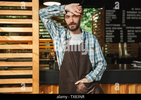 Ritratto di bello barista uomo che indossa il grembiule sorridere mentre lavora in street cafe o coffeehouse outdoor Foto Stock