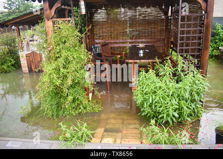 Grandi inondazioni di acqua dopo un imponente tempesta di pioggia. Il giardino e le piante sono coperte con acqua sporca. Molti danni dopo il forte temporale con la celebrazione della santa messa Foto Stock