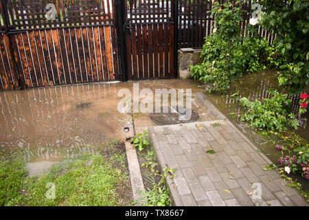 Grandi inondazioni di acqua dopo un imponente tempesta di pioggia. Il giardino e le piante sono coperte con acqua sporca. Molti danni dopo il forte temporale con la celebrazione della santa messa Foto Stock