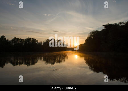Alba e tramonto su Salhouse ampia, il Parco Nazionale Broads del Norfolk, Maggio, visto da barca a barca vacanza, alba sul lago e alberi. Foto Stock