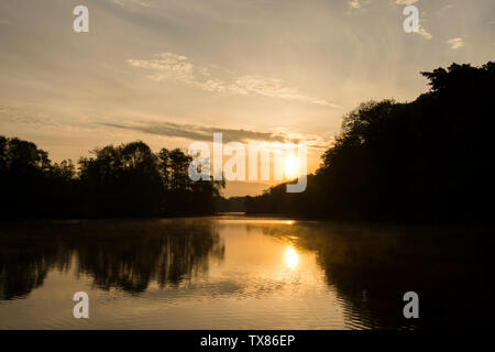 Alba e tramonto su Salhouse ampia, il Parco Nazionale Broads del Norfolk, Maggio, visto da barca a barca vacanza, alba sul lago e alberi. Foto Stock