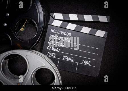 Più bobine di pellicola e un clapboard su uno sfondo di legno. Film, Hollywood, industria del divertimento di oggetti Foto Stock