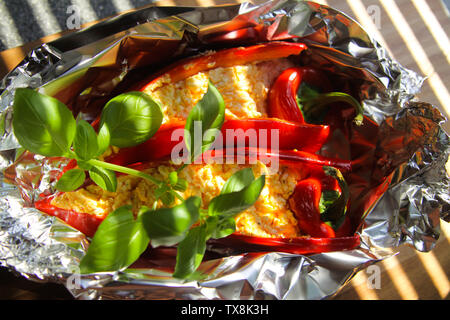 Close up farcite peperone rosso peperoni con pecora formaggio feta condito con peperoncino piccante alla griglia in un foglio di alluminio Foto Stock