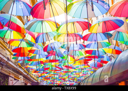 Multi-colore sfondo ombrelloni. Ombrelloni colorati galleggiante sopra la strada. Decorazione di strada. Foto Stock