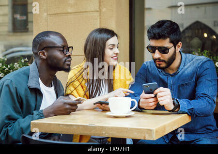 Tre felice multiculturale amici chiacchierare insieme all'outdoor cafe Foto Stock