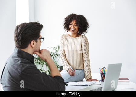 Vista laterale di Felice giovani colleghi parlando e cercando di ogni altro mentre è in ufficio Foto Stock