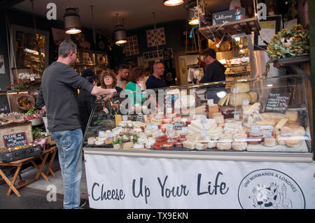 Gli amanti dello shopping a un mercato del formaggio in stallo nel mercato di Borough, Londra, Inghilterra Foto Stock