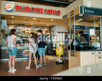 Stuttgart, Germania - 15 AGO 2018: vista posteriore del viaggiatore la famiglia presso il contatore di Burger King ristorante al distributore Esso in Germania in attesa di mettere ordine e ottieni il fast-food lontano Foto Stock