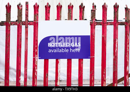 Gas in bottiglia disponibile qui segno sulla ringhiera rossa recinzione Foto Stock