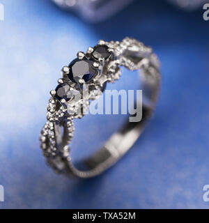 Anello oro bianco con pietre preziose su sfondo blu Foto Stock