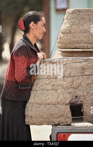 Giovane donna in forni di abbigliamento-fango locali pronti per il trasporto. Hotan-Xinjiang-Cina-0186 Foto Stock