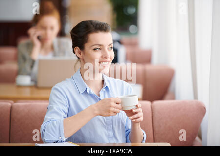 Donna di successo di bere il caffè nella caffetteria Foto Stock