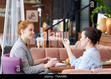 Giovani donne che condividono idee durante il pranzo Foto Stock