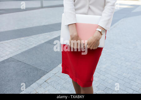La sezione centrale verticale di elegante giovane donna indossa il mantello rosso e tenendo laptop all'aperto, spazio di copia Foto Stock