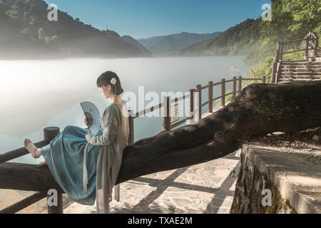 Dongjiang nebbia mattutina 2 (nella prima mattina di estate, vi è nebbia di mattina su Xiao Dongjiang. Una donna in costume antico gode di uno splendido scenario sulla superficie del fiume). Foto Stock